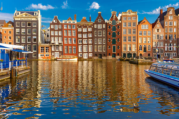 Damrak Beautiful typical Dutch dancing houses at the Amsterdam canal Damrak in sunny day, Holland, Netherlands.